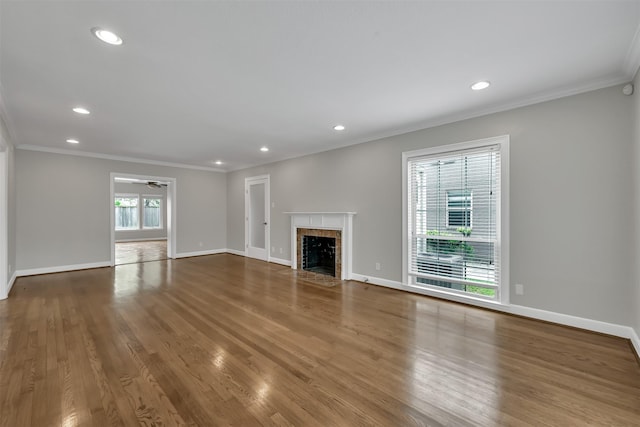 unfurnished living room with baseboards, wood finished floors, a fireplace, and crown molding