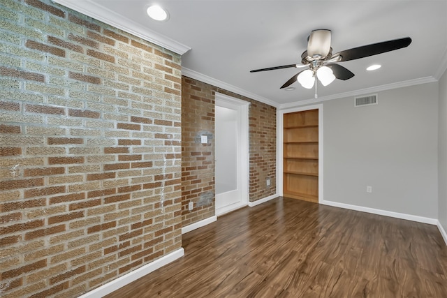 unfurnished room featuring wood finished floors, visible vents, brick wall, baseboards, and crown molding