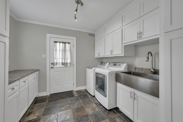 laundry room with visible vents, washing machine and dryer, stone tile flooring, cabinet space, and a sink