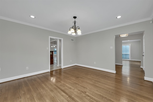 empty room featuring visible vents, crown molding, baseboards, and wood finished floors