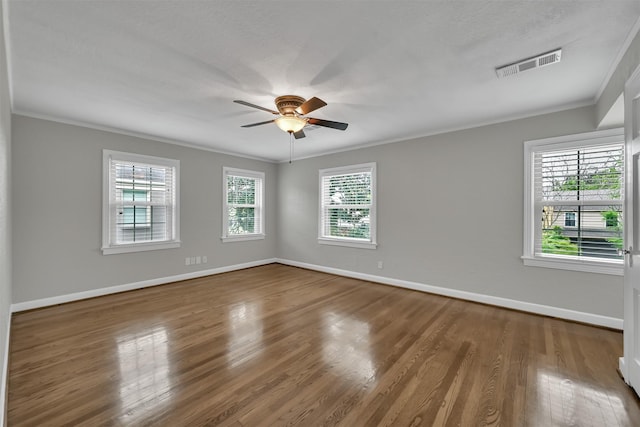 spare room featuring wood finished floors, visible vents, baseboards, and ornamental molding