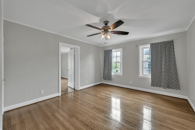 empty room featuring a ceiling fan, wood finished floors, baseboards, and ornamental molding