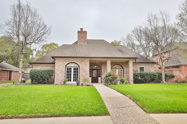 view of front facade featuring french doors, brick siding, a chimney, and a front lawn