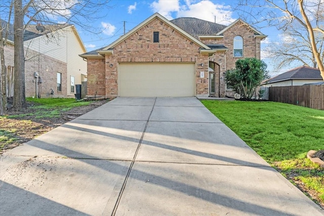 traditional-style home with brick siding, fence, concrete driveway, a front yard, and an attached garage