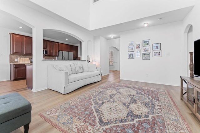 living area with recessed lighting, light wood-type flooring, and baseboards