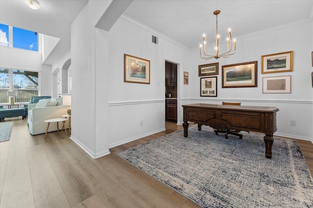 office space with wood finished floors, visible vents, arched walkways, ornamental molding, and a notable chandelier