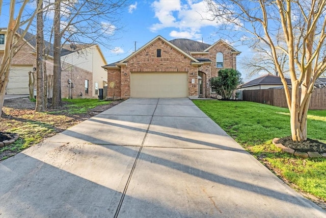 traditional-style home with fence, an attached garage, a front lawn, concrete driveway, and brick siding