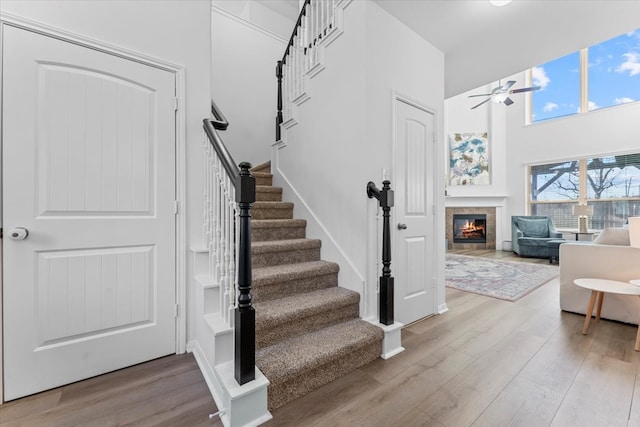 stairs featuring a ceiling fan, wood finished floors, and a fireplace