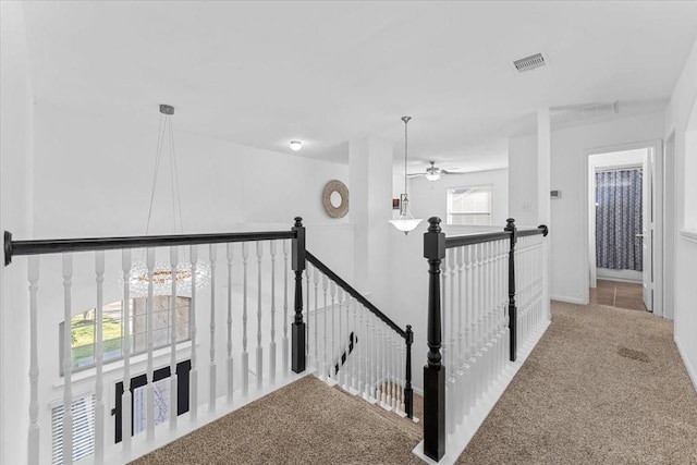 hall featuring carpet, an upstairs landing, and visible vents