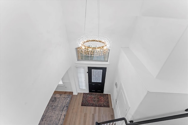 entryway featuring a notable chandelier, wood finished floors, baseboards, and a towering ceiling