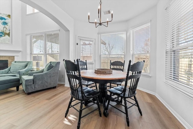 dining space with a fireplace, light wood-style floors, and baseboards