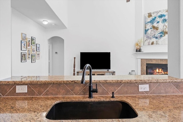 kitchen featuring light stone counters, a tile fireplace, and a sink