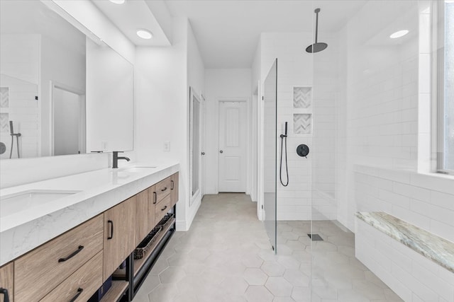 bathroom with double vanity, a walk in shower, and a sink