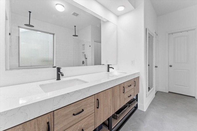 bathroom with a sink, a stall shower, and double vanity