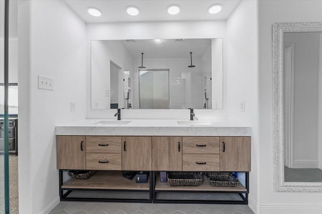 bathroom featuring double vanity, baseboards, a shower stall, and a sink