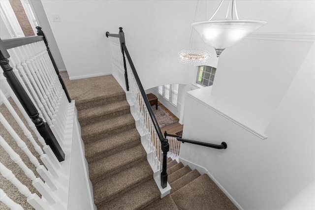 staircase featuring baseboards, carpet, and an inviting chandelier