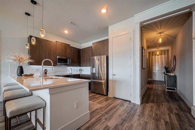 kitchen featuring visible vents, a sink, dark wood finished floors, appliances with stainless steel finishes, and light countertops