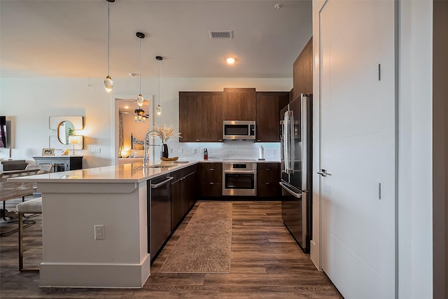 kitchen featuring visible vents, dark brown cabinets, a peninsula, stainless steel appliances, and a sink