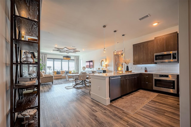 kitchen with visible vents, open floor plan, stainless steel appliances, a peninsula, and light countertops