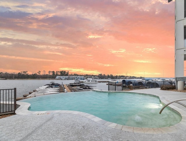 view of pool featuring a patio area, a water view, and fence