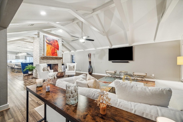 living area featuring vaulted ceiling with beams, baseboards, ceiling fan with notable chandelier, a fireplace, and wood finished floors