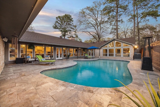 pool at dusk featuring a patio area, french doors, a fenced in pool, and central AC