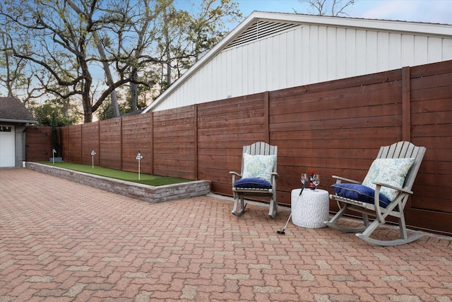 view of patio featuring decorative driveway, a fenced backyard, and a garage