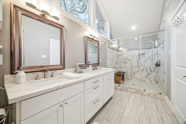 full bathroom with double vanity, a marble finish shower, and a sink