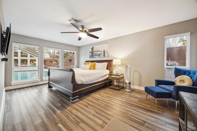 bedroom featuring visible vents, multiple windows, baseboards, and wood finished floors