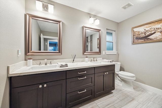 bathroom with double vanity, toilet, visible vents, and a sink