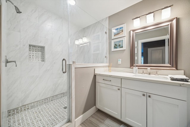 bathroom with a stall shower, vanity, and baseboards