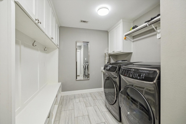 washroom with visible vents, baseboards, wood tiled floor, cabinet space, and separate washer and dryer