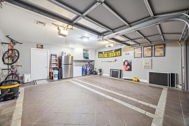 garage with visible vents, a garage door opener, and freestanding refrigerator