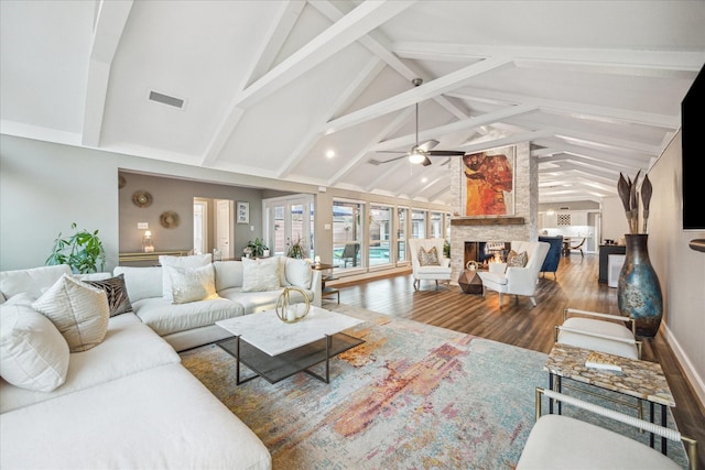 living area with wood finished floors, high vaulted ceiling, ceiling fan, a stone fireplace, and beamed ceiling