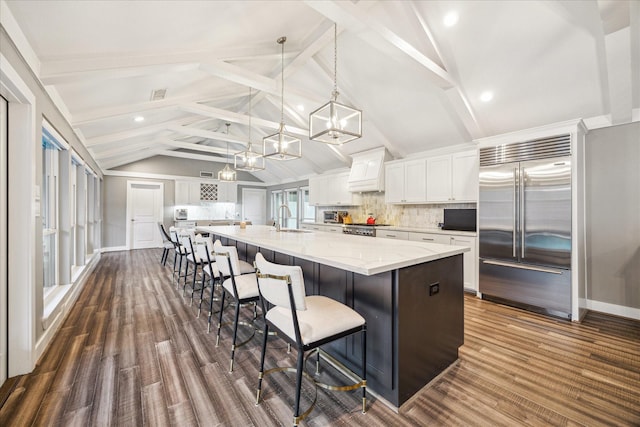 kitchen with a sink, a chandelier, stainless steel built in refrigerator, and white cabinets