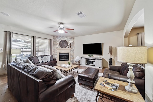 tiled living area featuring a fireplace, visible vents, and ceiling fan