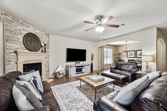 tiled living area featuring ceiling fan with notable chandelier, visible vents, arched walkways, and a large fireplace