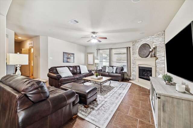 living room featuring visible vents, a fireplace, a ceiling fan, and dark tile patterned flooring