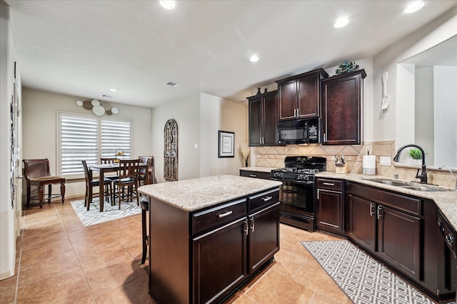 kitchen with visible vents, black appliances, a sink, light stone counters, and decorative backsplash