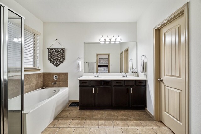 bathroom with tile patterned flooring, double vanity, a bath, and a sink