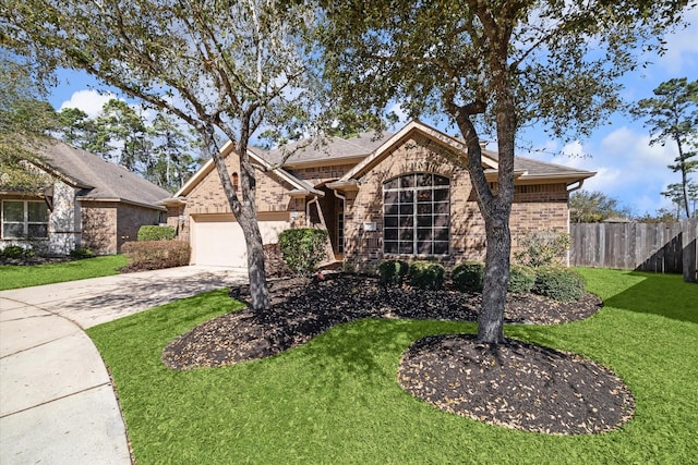 view of front facade featuring brick siding, fence, a front yard, driveway, and an attached garage