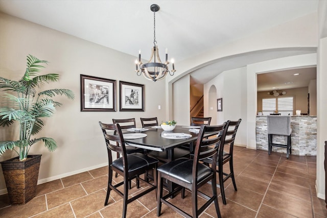 dining room with baseboards, arched walkways, and dark tile patterned flooring