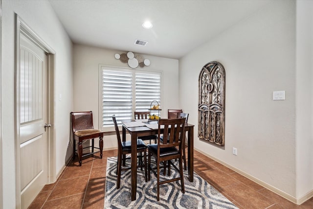 dining area with dark tile patterned floors, visible vents, and baseboards