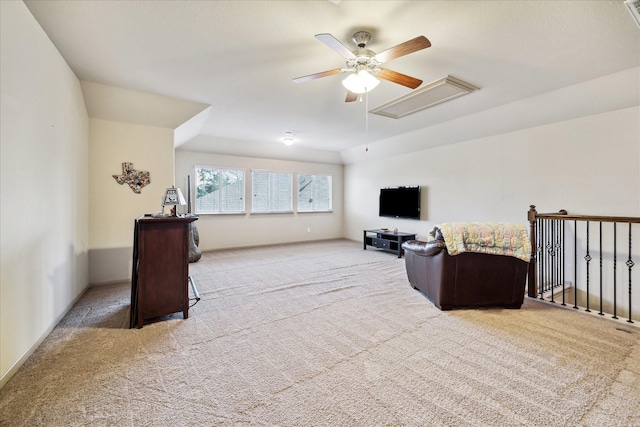 carpeted living area featuring attic access and a ceiling fan