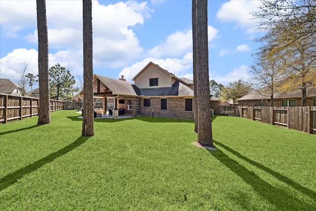 rear view of property with a patio area, a yard, a fenced backyard, and brick siding