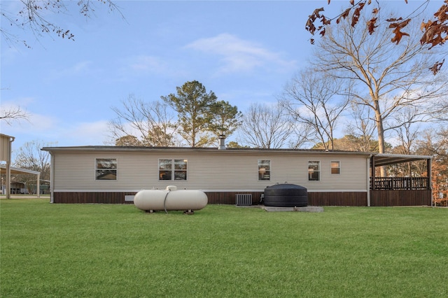 rear view of property with central air condition unit and a lawn