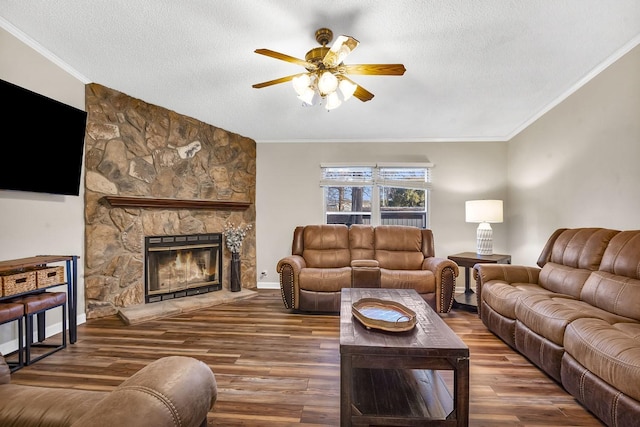 living room featuring a ceiling fan, wood finished floors, a fireplace, a textured ceiling, and crown molding