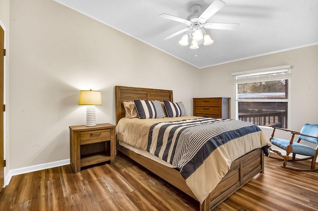 bedroom featuring wood finished floors, baseboards, arched walkways, ornamental molding, and vaulted ceiling