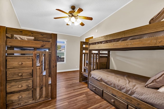 bedroom featuring lofted ceiling, wood finished floors, baseboards, and a textured ceiling