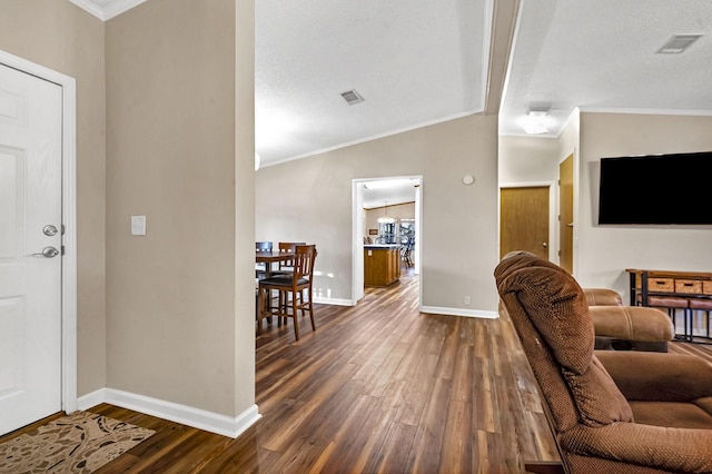 foyer entrance with baseboards, visible vents, dark wood-style flooring, and ornamental molding